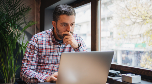 Man looking thoughtfully at his laptop.